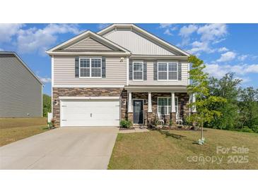 Two-story home featuring stone accents, a two-car garage, and a well-manicured lawn at 347 Carolina Hemlock Dr, Locust, NC 28097