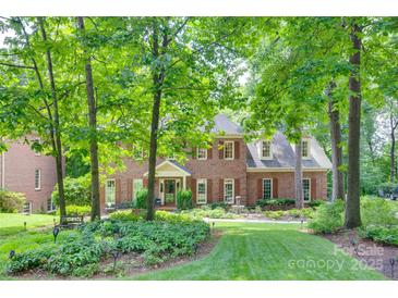 Stately two-story brick home featuring mature trees, lush landscaping, and a charming front garden at 10215 Balmoral Cir, Charlotte, NC 28210
