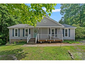 Charming single-story home with gray siding, a front porch, and lush green landscaping at 2934 Drakes Crossing Dr, Charlotte, NC 28262