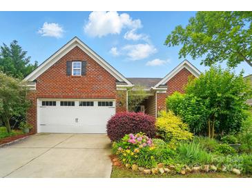 Charming brick home with a two-car garage and beautifully landscaped front yard featuring vibrant flowers and greenery at 6007 Edinburgh Ln # 214, Indian Land, SC 29707