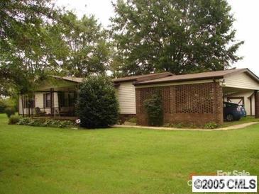Ranch-style home with a lush lawn, mature trees, and a covered carport, offering a blend of comfort and outdoor charm at 634 Lippard Farm Rd, Statesville, NC 28625