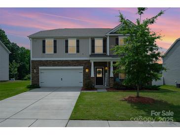 Charming two-story home featuring stone accents, a two-car garage, and a manicured front lawn at 711 Saddlebred Ln, Locust, NC 28097