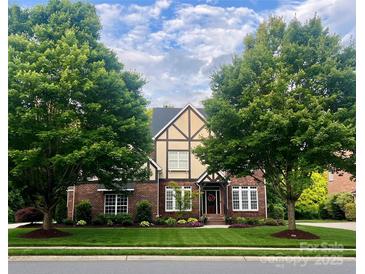 Charming two-story Tudor home with brick facade, gable roof, manicured lawn, and mature trees at 7620 Caspian Dr, Waxhaw, NC 28173