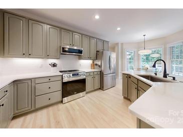 Modern kitchen with stainless steel appliances, light countertops, and light wooden floors at 118 Tayport Dr, Troutman, NC 28166