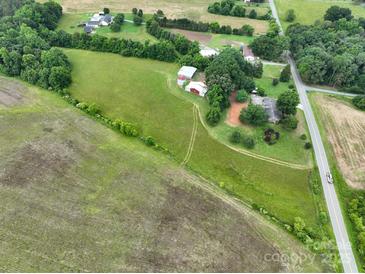 Expansive aerial view featuring farmland, trees, outbuildings and a two-story home near a road at 13101 Pine Bluff Rd, Midland, NC 28107