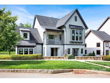 Charming home with a well-manicured front lawn, stone accents, and a mix of board and batten and stucco exterior at 14105 Ryker Way, Davidson, NC 28036