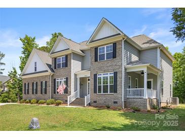 Two-story home with a well-manicured lawn and brick and gray siding, enhanced by a front porch at 3011 Waxhaw Crossing Dr, Waxhaw, NC 28173