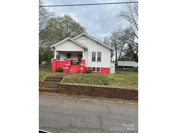 Charming home featuring a covered front porch, vibrant red foundation, and a detached carport at 325 N Caldwell Ave, Newton, NC 28658