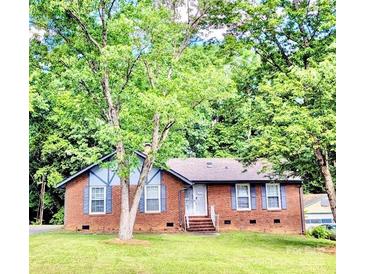 Charming brick home with a well-manicured lawn and mature trees, offering shade and curb appeal at 7133 Tall Tree Ln, Charlotte, NC 28214