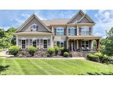 Beautiful two-story home boasts impeccable landscaping and a welcoming front porch at 9011 Kensington Forest Dr, Harrisburg, NC 28075