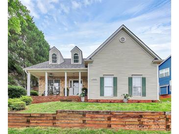 Charming two-story home featuring a stone porch, dormer windows, green shutters, and a beautifully landscaped front yard at 10449 Quiet Bay Ct, Charlotte, NC 28278