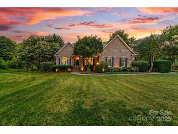 Charming brick home with lush lawn, manicured landscaping, and inviting curb appeal at sunset at 1115 Maremont Ct, Matthews, NC 28104