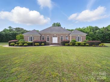 Charming brick home featuring a meticulously landscaped front yard with lush green grass and manicured bushes at 1340 Canter Ln, York, SC 29745