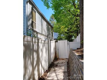 View of the side yard, showing a white fence and a path to a gated entrance and retaining wall at 7107 Stonington Ln, Charlotte, NC 28227