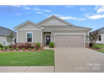 Charming one-story home featuring a well-manicured lawn, a two-car garage, and decorative landscaping at 1344 Sweet Pea St, Monroe, NC 28110