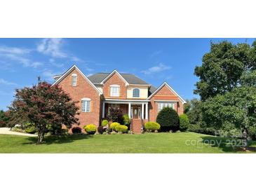 Charming brick home featuring a manicured lawn, mature trees, and inviting front entrance at 140 Hunters Hill Dr, Statesville, NC 28677