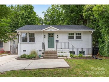 Charming white brick home featuring a beautifully landscaped front yard and a welcoming green front door at 1713 Shamrock Dr, Charlotte, NC 28205