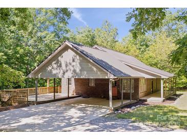 Charming brick home featuring a metal roof, covered carport and a spacious wooden deck surrounded by lush greenery at 3090 Goblet Rd, Richburg, SC 29729