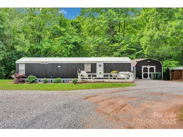 Charming home with a wooden deck and a gravel driveway surrounded by lush greenery and a storage shed at 2289 Mccloud St, Denver, NC 28037