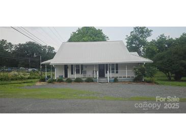 Charming one story home featuring a metal roof, fresh landscaping and rocking chair front porch at 804 N Main St, Oakboro, NC 28129