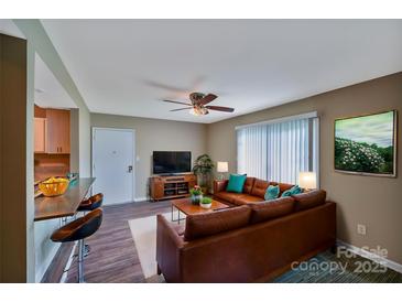 Inviting living room features a brown leather couch and a mounted TV at 809 High Meadow Ln # F, Charlotte, NC 28217