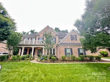 Charming two-story brick home featuring a beautiful front yard and a lovely balcony with decorative railings at 10508 Kristens Mare Dr, Charlotte, NC 28277