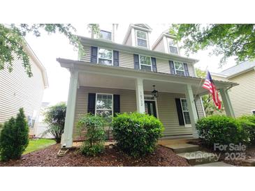Charming home showcasing a covered front porch, complemented by well-maintained landscaping and an American flag at 10732 Trolley Run Dr, Cornelius, NC 28031