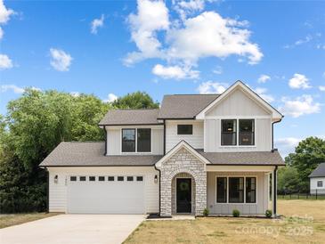 Charming two-story home featuring stone arched entry, attached garage, and manicured lawn, under a bright blue cloudy sky at 1490 White Hall Pl, Gastonia, NC 28056
