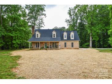 Charming brick home with a cozy front porch, nestled among mature trees at 15025 Barbee Rd, Stanfield, NC 28163