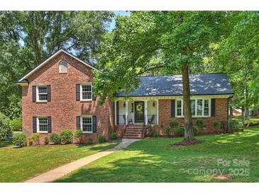 Charming brick home featuring a welcoming front porch and beautifully landscaped front yard at 2301 Seth Thomas Rd, Charlotte, NC 28210