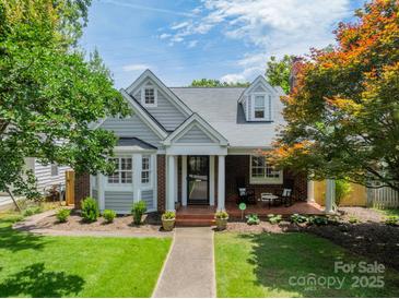 Charming gray and brick home with manicured lawn and inviting front porch with rocking chairs at 2021 Charlotte Dr, Charlotte, NC 28203
