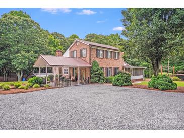 Charming two-story brick home featuring an attached covered patio and a spacious gravel driveway at 211 Drive Inn Rd, Locust, NC 28097