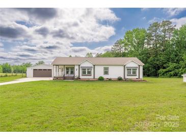 Charming single-story home with a covered porch, green lawn, and detached garage, providing ample space and curb appeal at 326 Teeter Rd, Mooresville, NC 28115