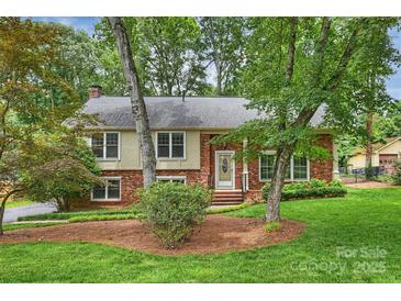 Charming brick home with lush front yard and mature trees, offering a serene and inviting curb appeal at 7050 Knightswood Dr, Charlotte, NC 28226