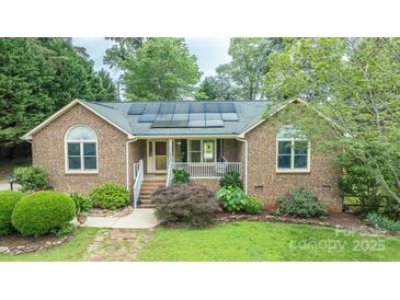 Charming brick home featuring solar panels, a cozy front porch, and beautifully landscaped front yard at 8259 Camelia Ln, Denver, NC 28037