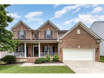 Charming two-story brick home featuring a welcoming front porch, attached two-car garage, and well-maintained landscaping at 10198 Tintinhull Dr, Fort Mill, SC 29707