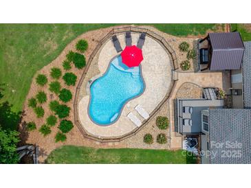 Aerial view of a backyard pool surrounded by a paver patio, lounge chairs, and lush landscaping at 1028 Pocono Pl, Newton, NC 28658
