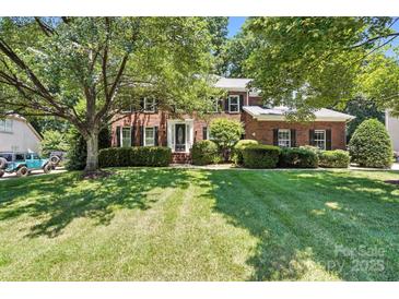 Stately brick home with a lush, green lawn and mature trees providing shade at 21621 Crown Lake Dr, Cornelius, NC 28031