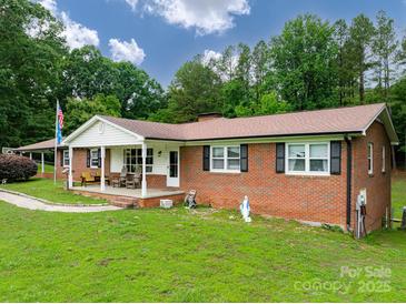Charming brick home featuring a covered front porch, spacious lawn, and mature trees at 310 Yarbro Rd, Kings Mountain, NC 28086