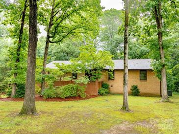 Quaint brick home nestled among mature trees and lush greenery, offering privacy and a serene setting at 5109 Goldcrest Dr, Indian Trail, NC 28079