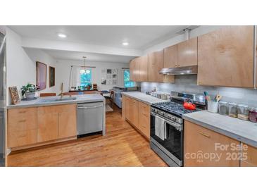 Bright kitchen with stainless steel appliances, gray backsplash, and wooden cabinets at 1344 Shannonhouse Dr, Charlotte, NC 28215