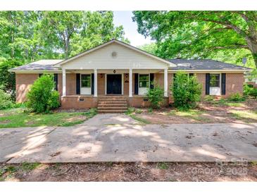 Charming brick home features a quaint front porch, mature trees, and lush landscaping at 257 Amity Dr, York, SC 29745
