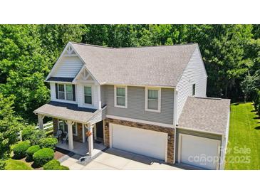 Attractive two-story home featuring gray siding, stone accents, attached garages, and a charming front porch at 3106 Crosswind Dr, Fort Mill, SC 29707