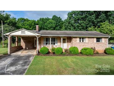 Charming brick home with manicured lawn and decorative white railing on the front porch at 518 W School St, Maiden, NC 28650