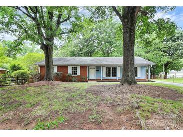 Charming single-story home featuring a mix of brick and siding with a manicured lawn and mature trees at 7118 April Ridge Ln, Charlotte, NC 28215