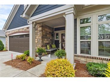 Inviting front porch featuring stone accents, neutral bench, and lush landscaping at 1712 Askern Ct, Waxhaw, NC 28173