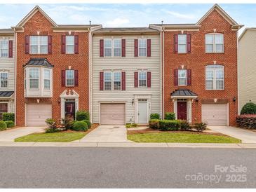 Charming townhome with brick and siding exterior, red shutters, well-kept lawn, and driveway with attached garage at 2169 Belle Vernon Ave, Charlotte, NC 28210
