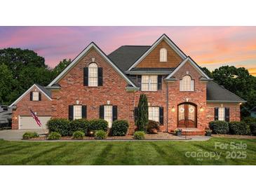 Charming brick home with manicured lawn, decorative shutters, and inviting front entrance at dusk at 4359 Whitetail Ln, Midland, NC 28107
