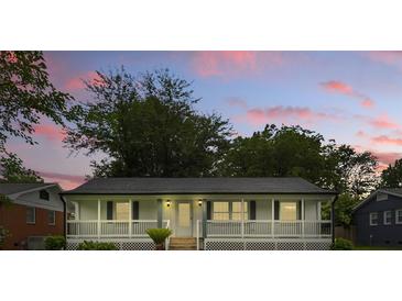 Charming home featuring a welcoming front porch, complemented by the lush, green landscape and a backdrop of the sunset at 4838 Keats Ave, Charlotte, NC 28212