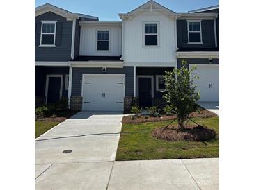 Modern two-story townhome with a one-car garage, manicured lawn, and neutral-colored exterior at 6114 Starview Ter, Charlotte, NC 28216